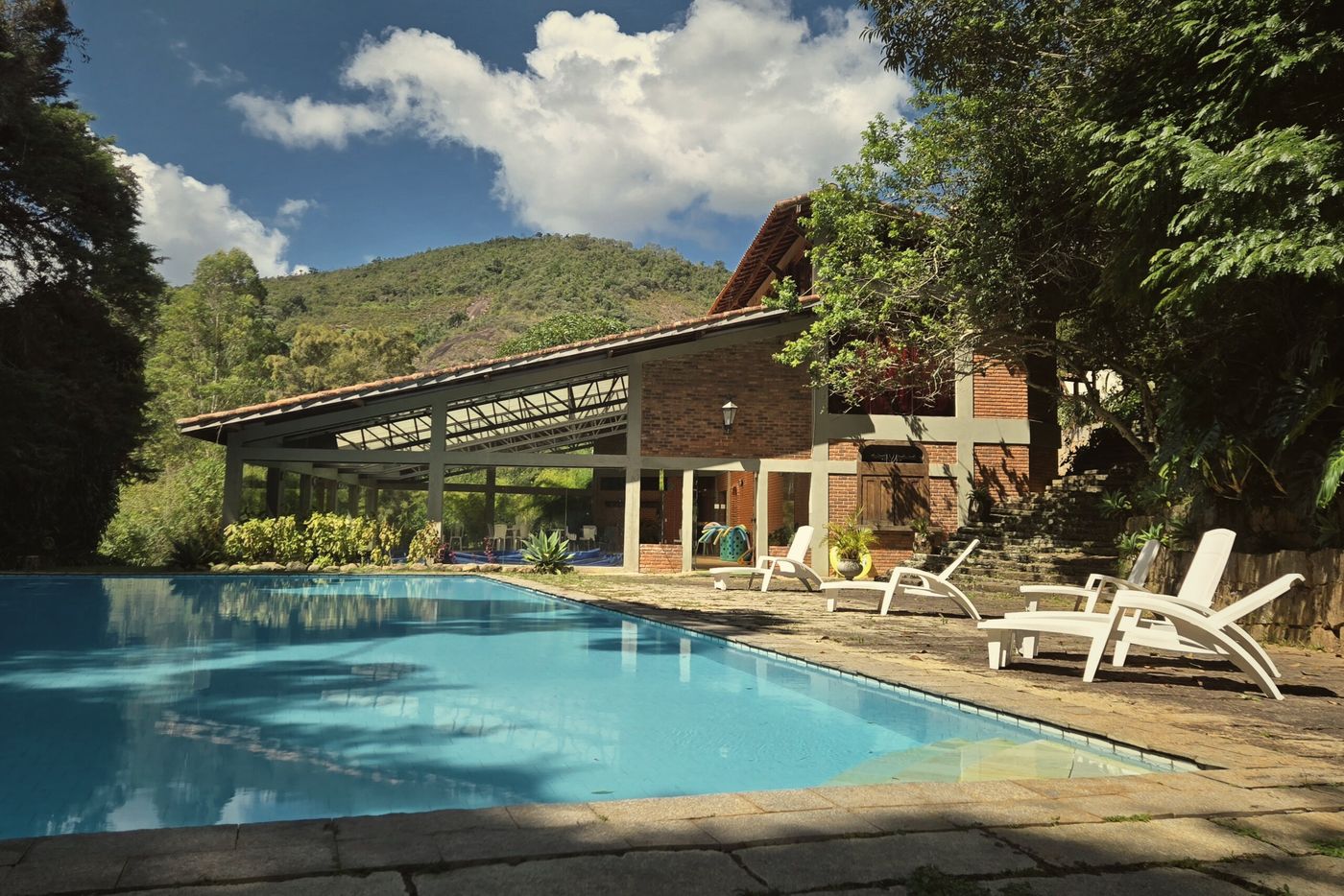 Piscina externa com espreguiçadeiras e a montanha ao fundo