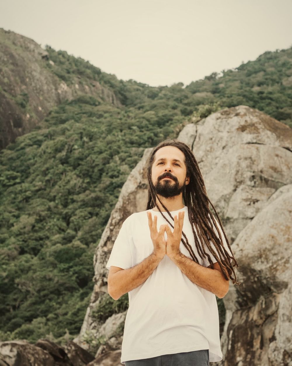Douglas Cruz em pé, mãos unidas, com a montanha ao fundo